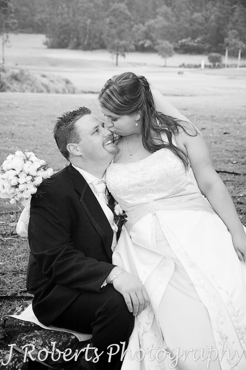 Bride sitting on grooms knee kissing his nose - wedding photography sydney